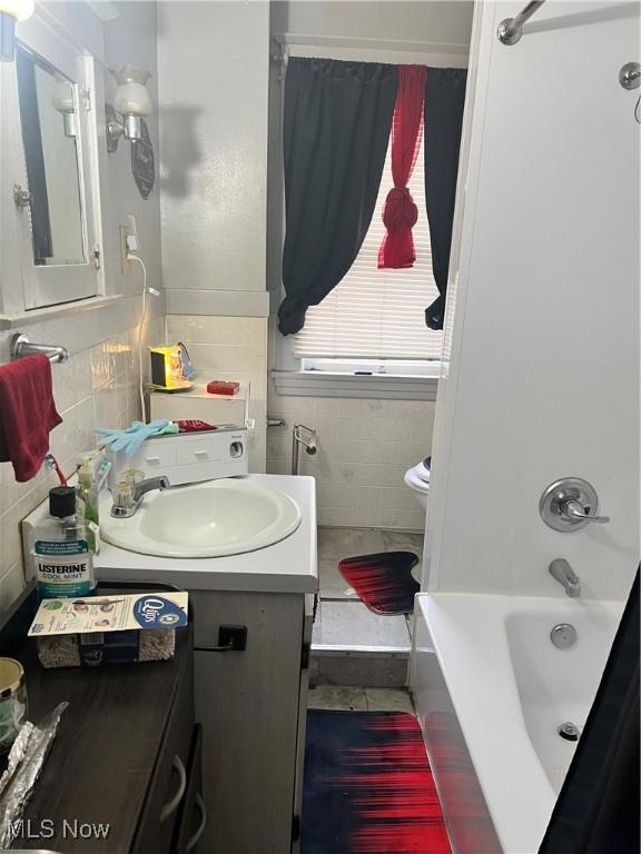 bathroom featuring toilet, shower / tub combination, tile walls, and vanity