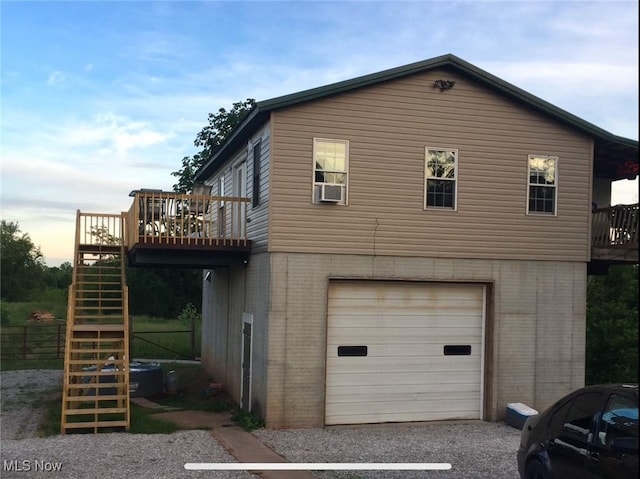 view of side of property with a garage, stairway, a deck, cooling unit, and brick siding