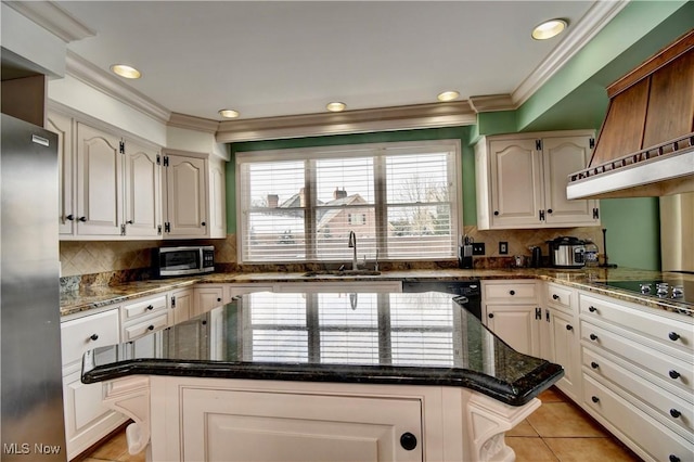 kitchen featuring light tile patterned floors, a center island, black appliances, white cabinetry, and a sink