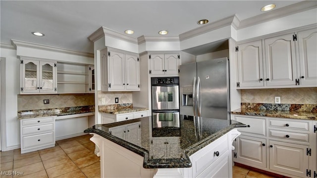 kitchen featuring a kitchen island, glass insert cabinets, dark stone countertops, stainless steel appliances, and white cabinetry