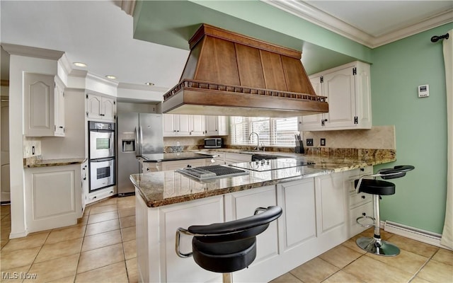 kitchen featuring stone counters, crown molding, appliances with stainless steel finishes, white cabinetry, and a peninsula