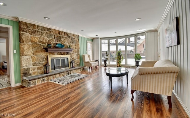 living area with recessed lighting, a fireplace, crown molding, and wood finished floors