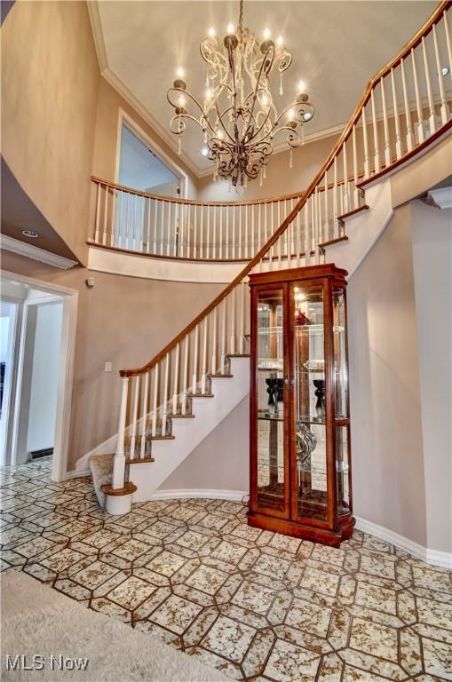 stairway featuring baseboards, a towering ceiling, and crown molding