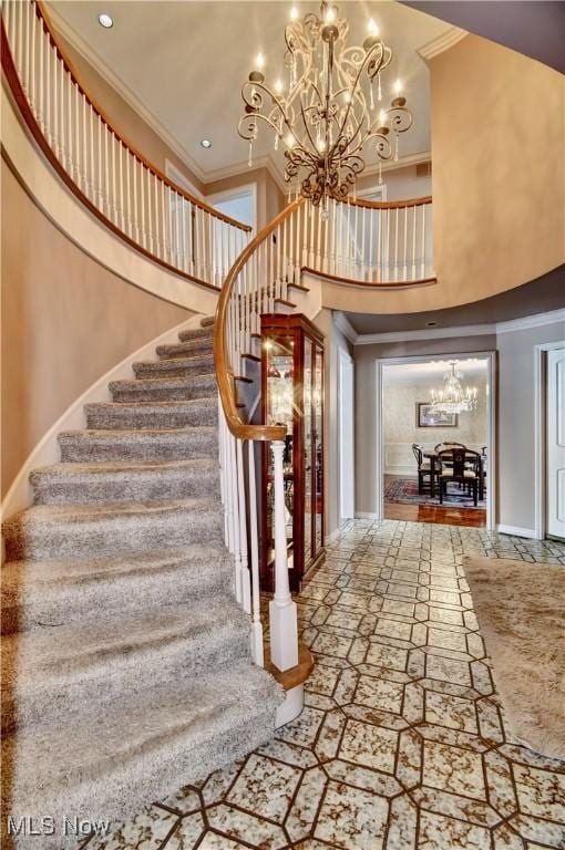 stairs with ornamental molding, baseboards, a notable chandelier, and a high ceiling