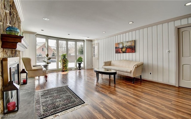 living area featuring recessed lighting, ornamental molding, wood finished floors, and a glass covered fireplace