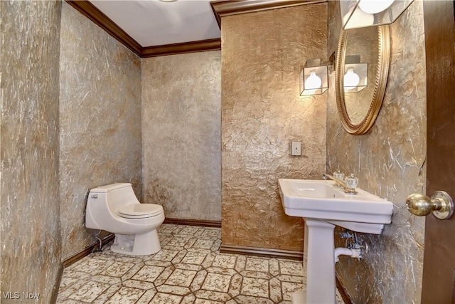 bathroom featuring baseboards, crown molding, and toilet