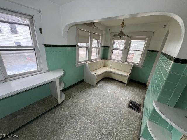 bathroom with wainscoting, visible vents, and tile walls