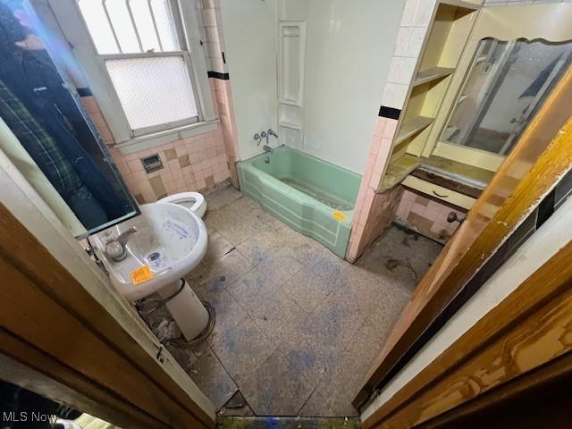 bathroom with shower / bath combination, toilet, and tile walls