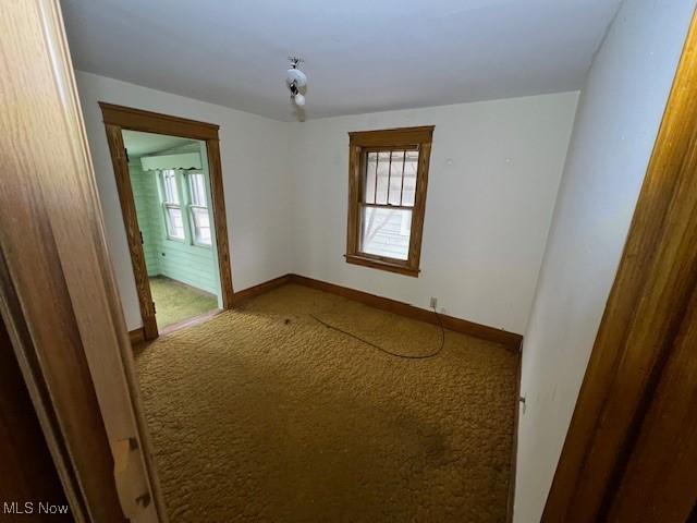 empty room featuring carpet floors and baseboards