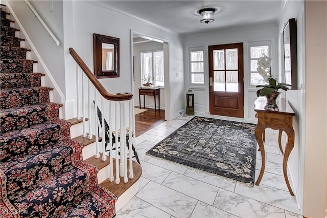 entryway with marble finish floor, baseboards, and crown molding