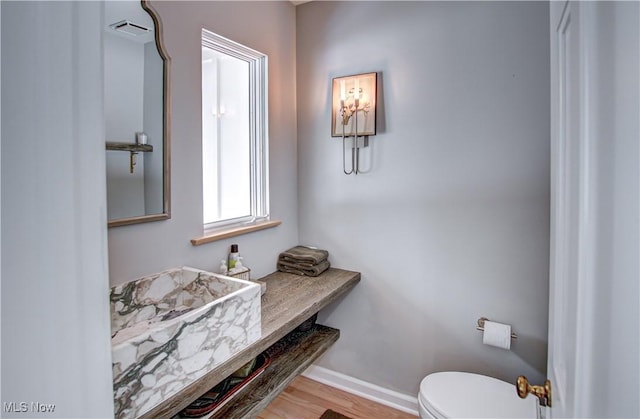 bathroom with wood finished floors, toilet, and baseboards