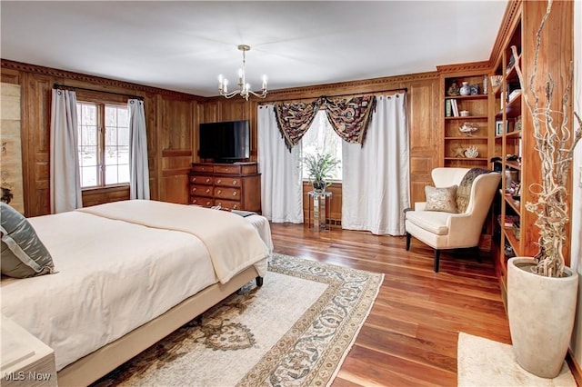 bedroom with wood walls, dark wood-style flooring, and a notable chandelier