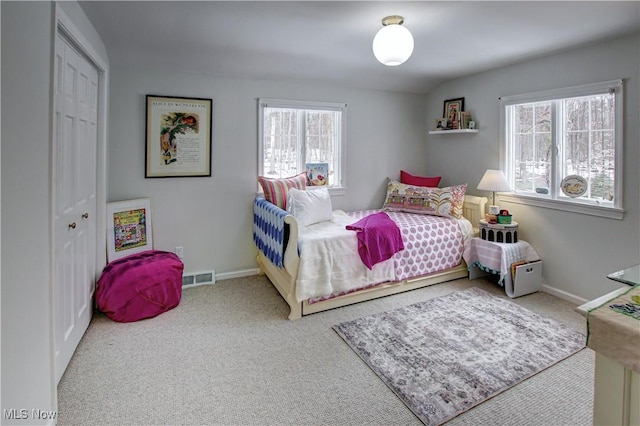 carpeted bedroom with a closet, visible vents, and baseboards