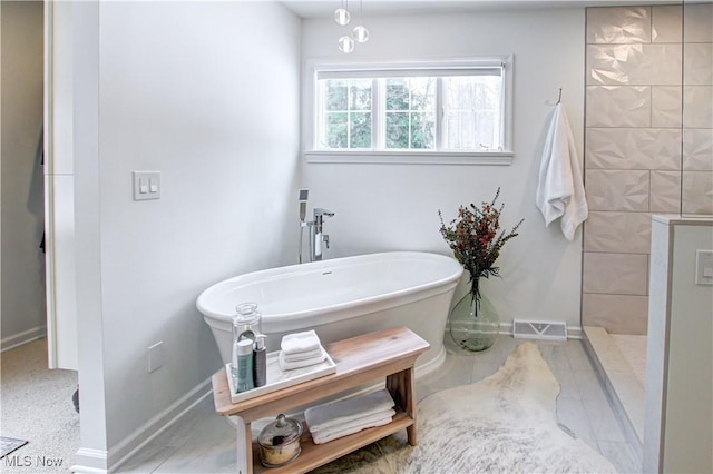 full bath with a soaking tub, baseboards, visible vents, and a tile shower