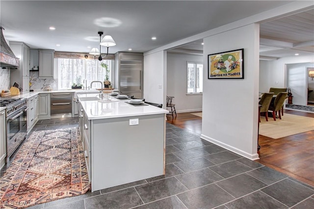 kitchen featuring appliances with stainless steel finishes, decorative light fixtures, a center island, light countertops, and gray cabinetry