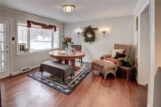 living area with ornamental molding, dark wood-style flooring, visible vents, and baseboards