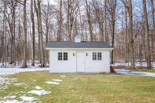 snow covered structure featuring a lawn and an outdoor structure