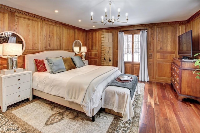 bedroom with wood walls, a chandelier, wood finished floors, and recessed lighting