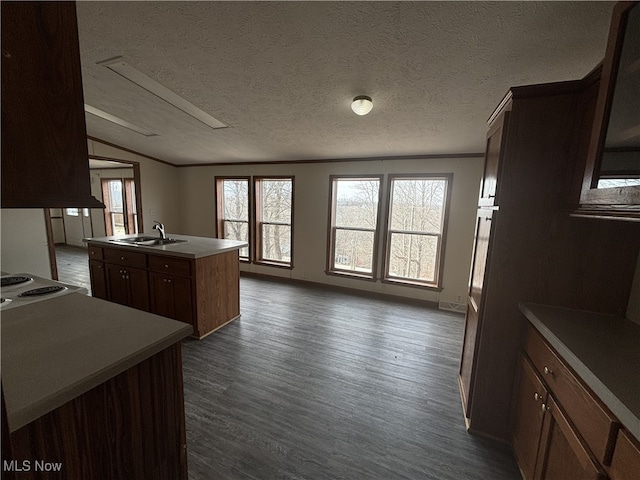 kitchen featuring a center island with sink, lofted ceiling, dark wood-style floors, stovetop, and a sink