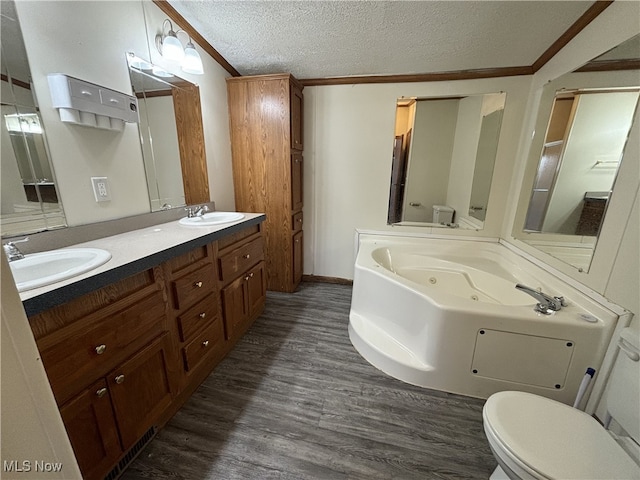 bathroom featuring a textured ceiling, wood finished floors, a sink, a whirlpool tub, and crown molding