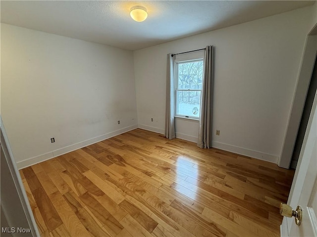 unfurnished room featuring light wood-type flooring and baseboards