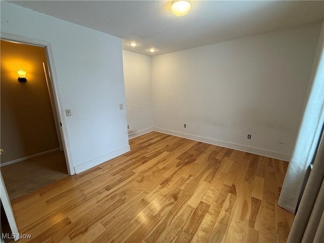 spare room featuring light wood-style floors and baseboards