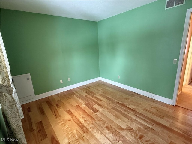 unfurnished room featuring light wood-style flooring, visible vents, and baseboards