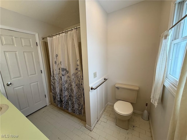 full bath with toilet, curtained shower, and baseboards