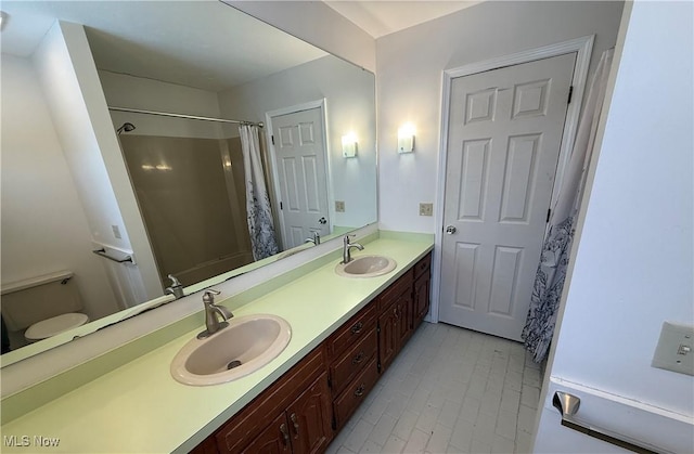 bathroom featuring a shower with shower curtain, a sink, toilet, and double vanity