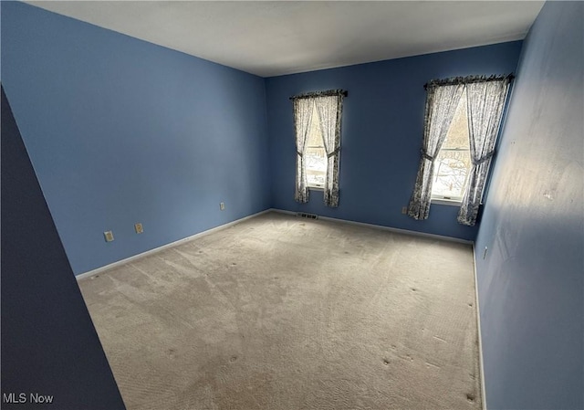 carpeted empty room featuring baseboards