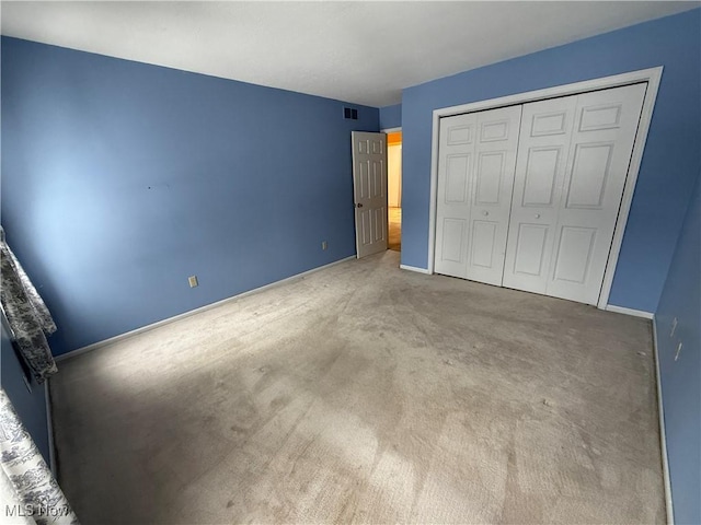 unfurnished bedroom with carpet, a closet, visible vents, and baseboards