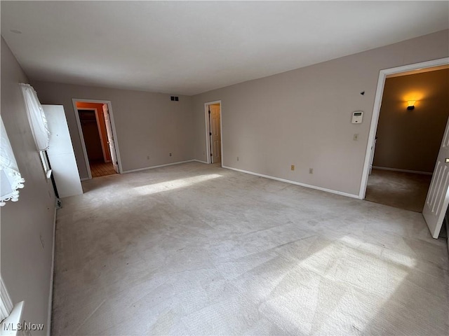 unfurnished room with light colored carpet, visible vents, and baseboards