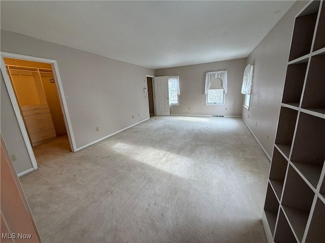 unfurnished room featuring light carpet and baseboards