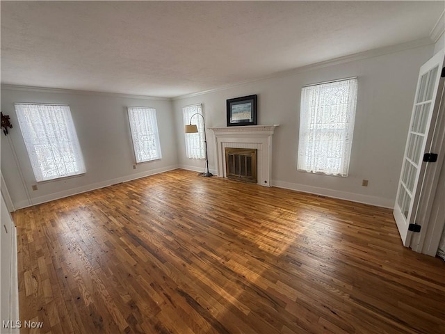 unfurnished living room with a fireplace with flush hearth, dark wood-type flooring, crown molding, and baseboards