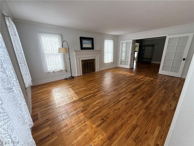 unfurnished living room featuring dark wood-style floors, a glass covered fireplace, and a wealth of natural light