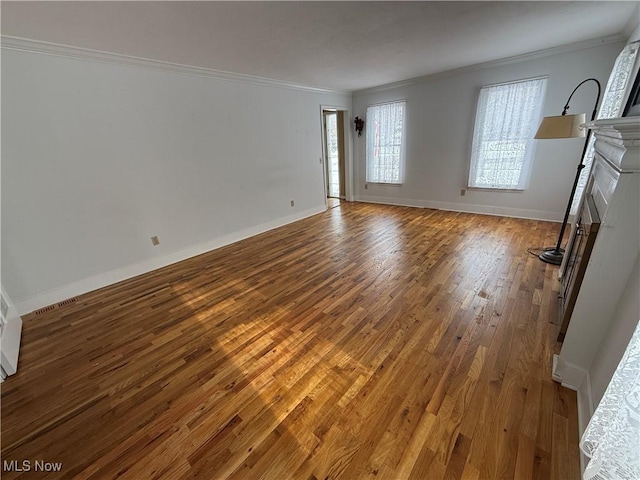 unfurnished living room featuring baseboards, a fireplace, wood finished floors, and crown molding