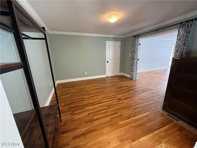 bedroom featuring baseboards, wood finished floors, and crown molding