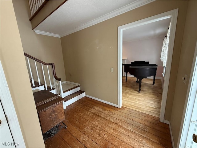 staircase with baseboards, ornamental molding, and wood finished floors