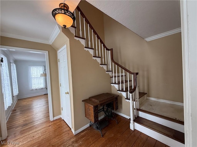 staircase with crown molding, baseboards, and wood finished floors