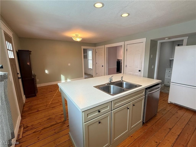 kitchen with dishwasher, freestanding refrigerator, a kitchen island with sink, light countertops, and a sink