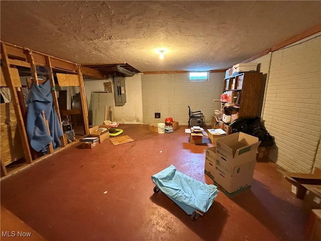 basement featuring electric panel and brick wall