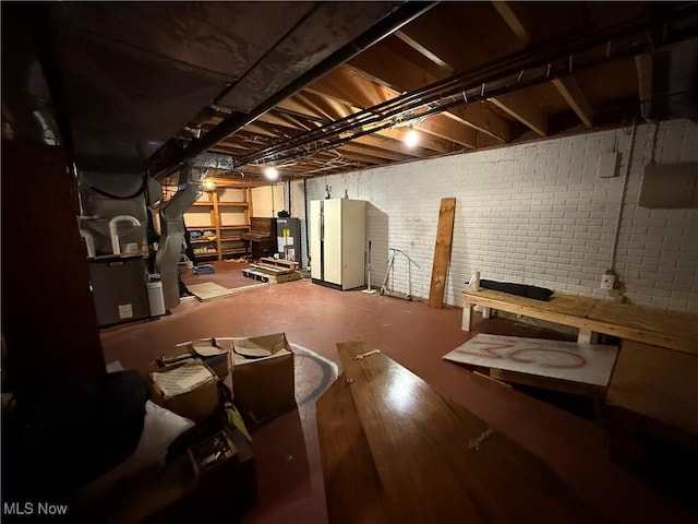 unfinished basement with water heater, brick wall, and freestanding refrigerator