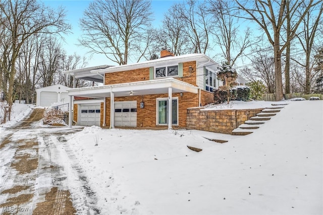 view of front of property featuring a garage, brick siding, and a chimney