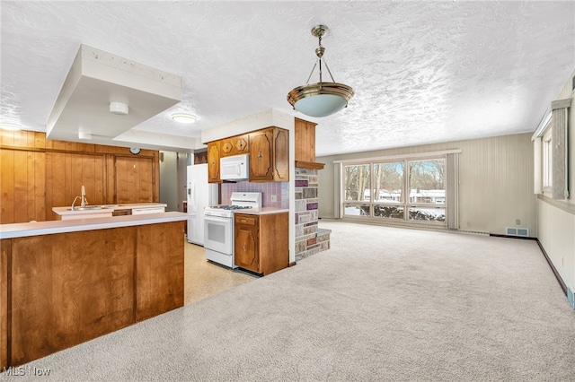 kitchen featuring white appliances, plenty of natural light, brown cabinetry, light countertops, and pendant lighting