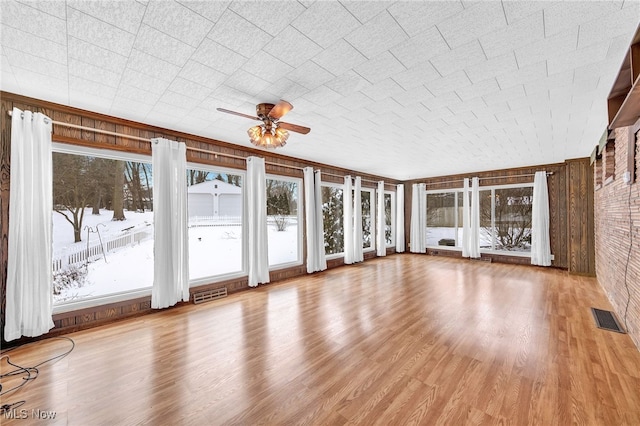 unfurnished sunroom featuring plenty of natural light, visible vents, and a ceiling fan