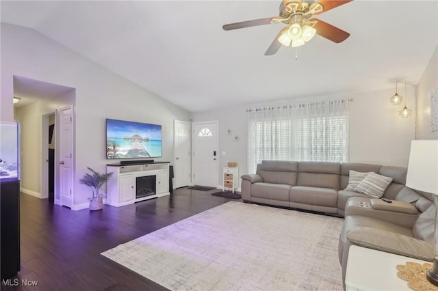 living room featuring lofted ceiling, a fireplace, wood finished floors, a ceiling fan, and baseboards