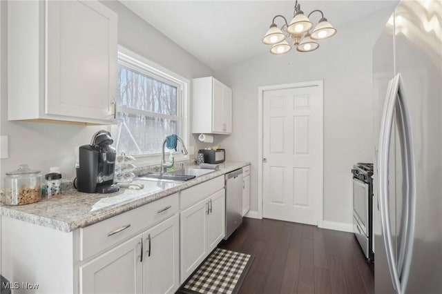 kitchen featuring lofted ceiling, a sink, white cabinets, hanging light fixtures, and appliances with stainless steel finishes