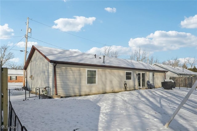 snow covered rear of property featuring fence