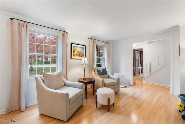 sitting room with light wood finished floors, stairs, baseboards, and crown molding