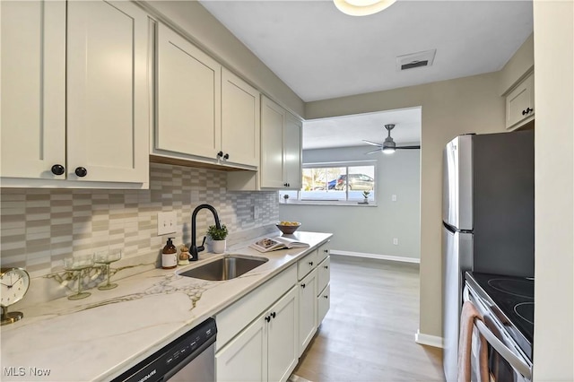 kitchen featuring visible vents, decorative backsplash, appliances with stainless steel finishes, a sink, and light stone countertops